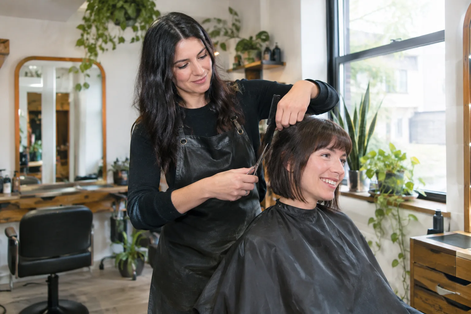 Une coiffeuse coupe les cheveux d’une cliente dans un petit salon